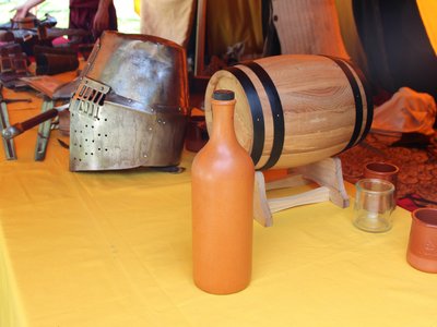 Compagnie Briselame - Table où reposent épées, casque, bouteille et tonneau pour un décor médiéval de la tente